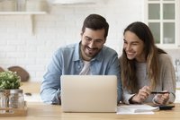 Bild: Eine Frau und ein Mann schauen fröhlich in den Laptop.