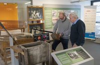 Bild: Zwei Männer, die im Museum in Mitterteich stehen und sich einige Stücke ansehen.